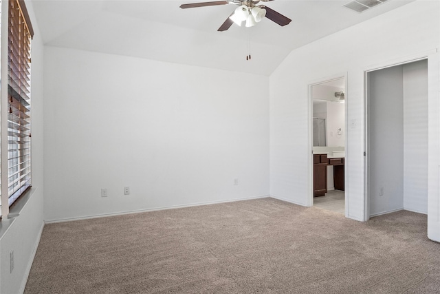 unfurnished bedroom with ceiling fan, connected bathroom, vaulted ceiling, and light carpet