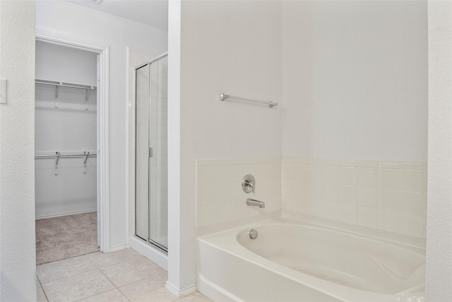 full bath with tile patterned floors, a walk in closet, a bath, and a shower stall