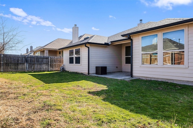 back of house with a patio, a chimney, a yard, and fence