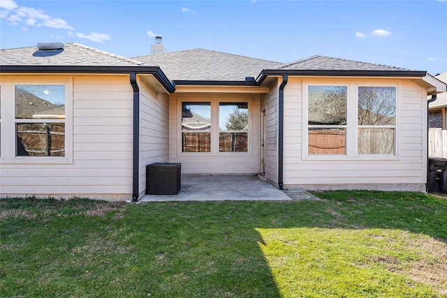 rear view of property featuring a patio area, a lawn, roof with shingles, and a chimney