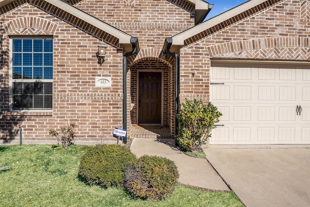 doorway to property featuring a garage and brick siding