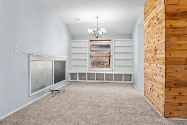 unfurnished living room featuring visible vents, carpet, built in features, vaulted ceiling, and an inviting chandelier