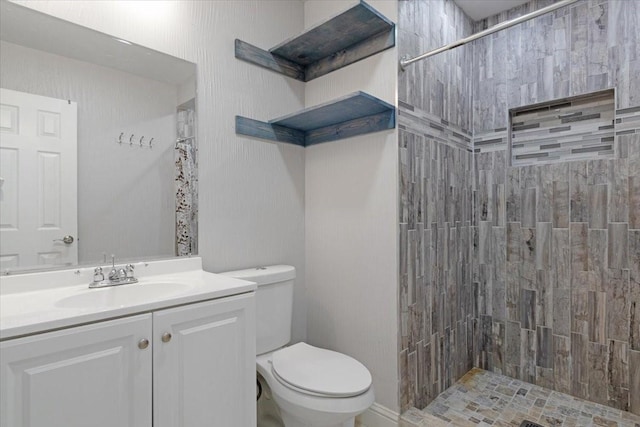 bathroom featuring vanity, toilet, and a tile shower