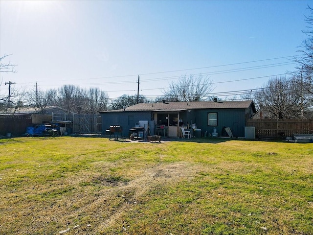 rear view of house with central AC unit and a yard