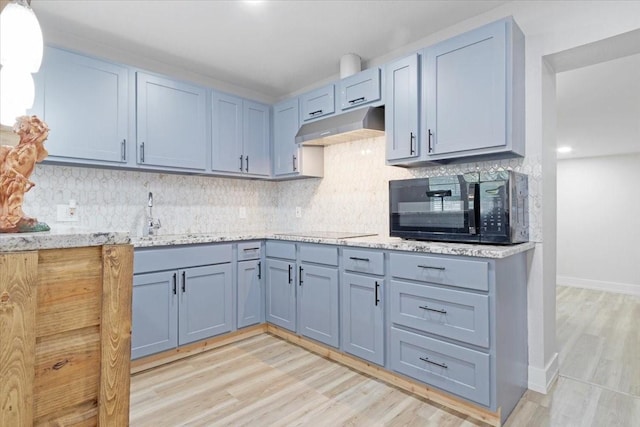 kitchen with sink, light hardwood / wood-style flooring, backsplash, and black appliances