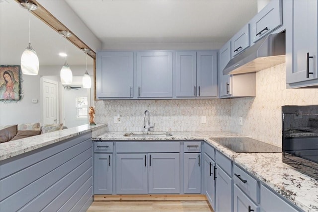 kitchen featuring decorative light fixtures, sink, backsplash, black electric stovetop, and light hardwood / wood-style flooring