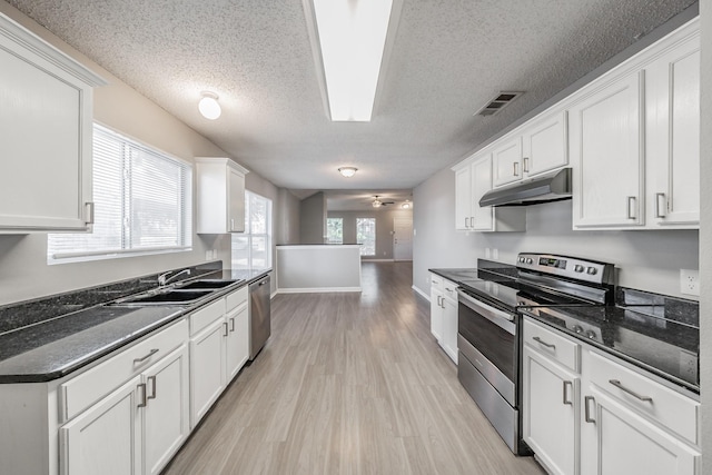 kitchen featuring sink, white cabinetry, dark stone countertops, appliances with stainless steel finishes, and light hardwood / wood-style floors