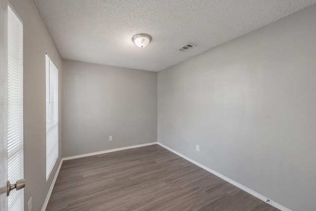 unfurnished room with dark wood-type flooring and a textured ceiling