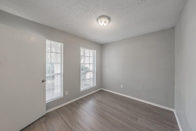 spare room featuring dark wood-type flooring and a textured ceiling