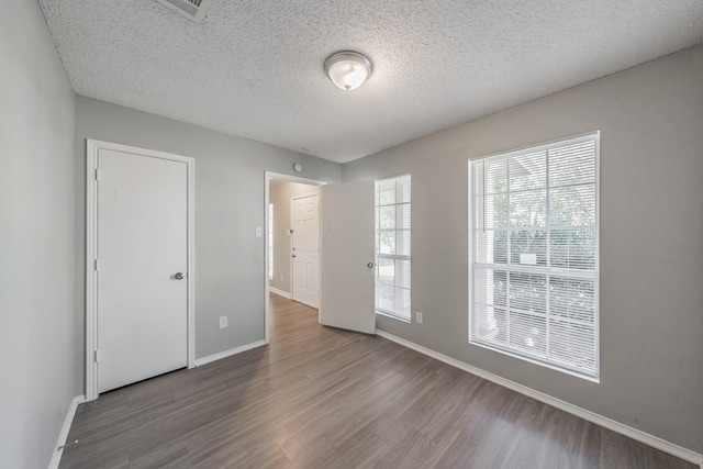 empty room with dark hardwood / wood-style floors and a textured ceiling