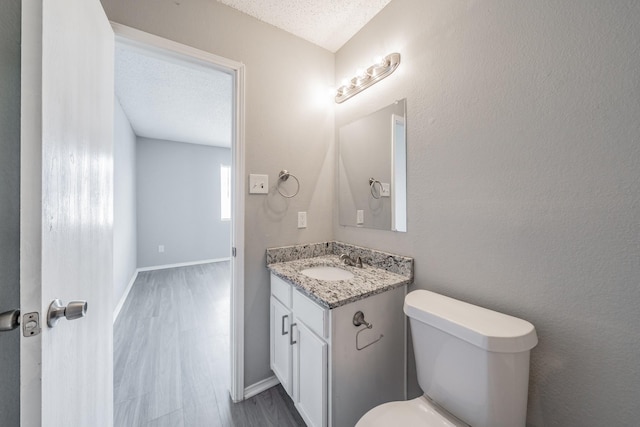 bathroom with vanity, wood-type flooring, a textured ceiling, and toilet