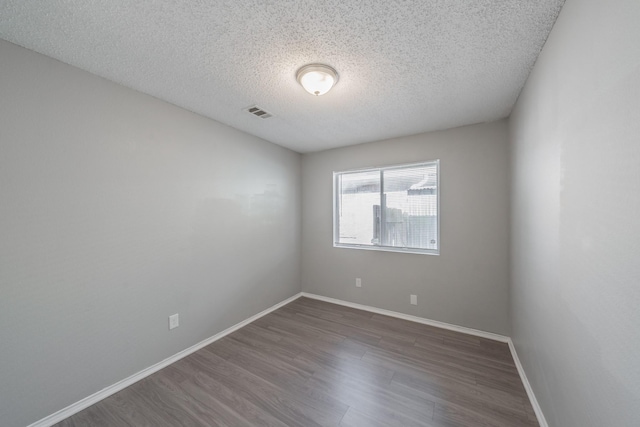 unfurnished room with dark hardwood / wood-style floors and a textured ceiling