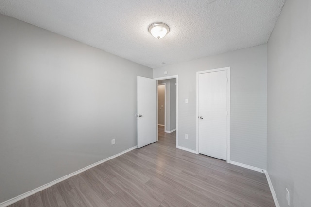 unfurnished bedroom featuring a closet, a textured ceiling, and light hardwood / wood-style floors