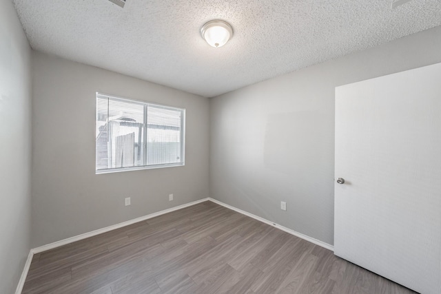 unfurnished room featuring hardwood / wood-style flooring and a textured ceiling