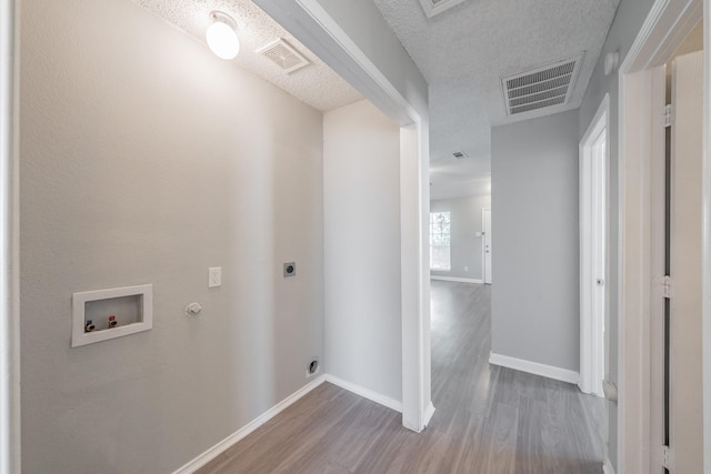 laundry area featuring gas dryer hookup, a textured ceiling, hardwood / wood-style flooring, washer hookup, and hookup for an electric dryer