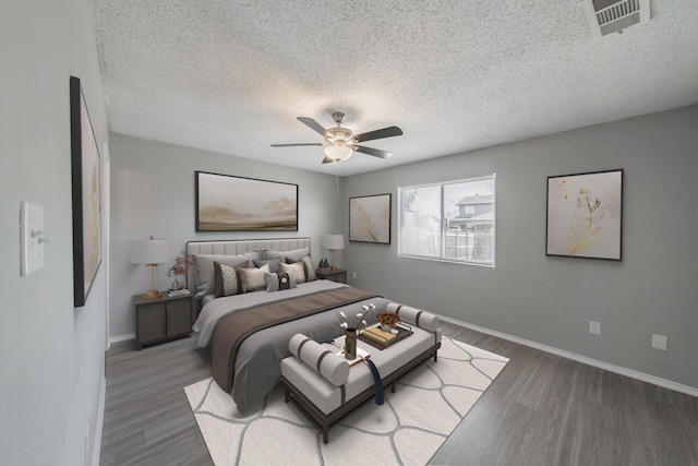 bedroom with dark hardwood / wood-style floors, a textured ceiling, and ceiling fan