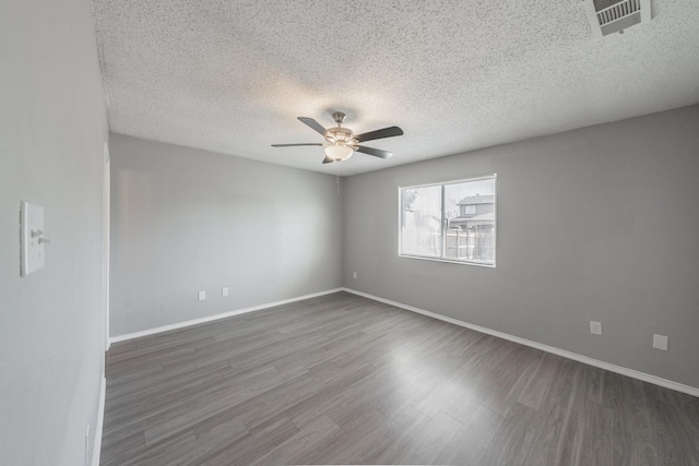 empty room with ceiling fan, dark hardwood / wood-style flooring, and a textured ceiling