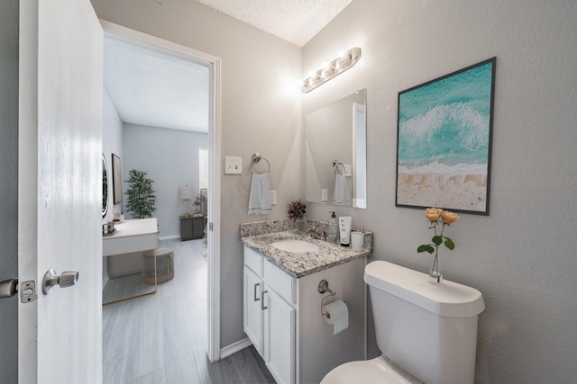 bathroom featuring vanity, hardwood / wood-style flooring, toilet, and a textured ceiling