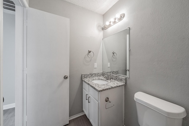 bathroom featuring vanity, a textured ceiling, and toilet