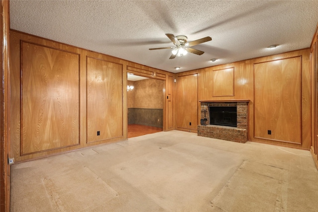 unfurnished living room with light carpet, a brick fireplace, wooden walls, and ceiling fan