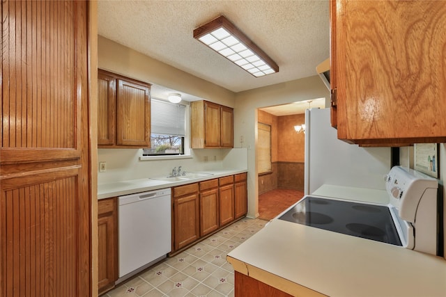 kitchen featuring sink, a textured ceiling, and white appliances