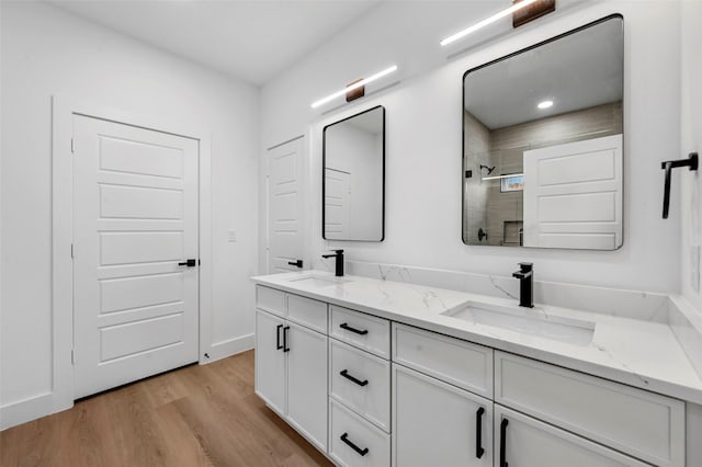 bathroom with hardwood / wood-style flooring, tiled shower, and vanity