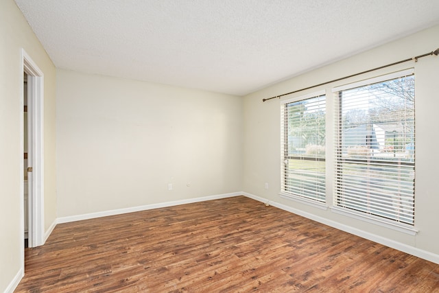 unfurnished room featuring dark wood-type flooring and a textured ceiling