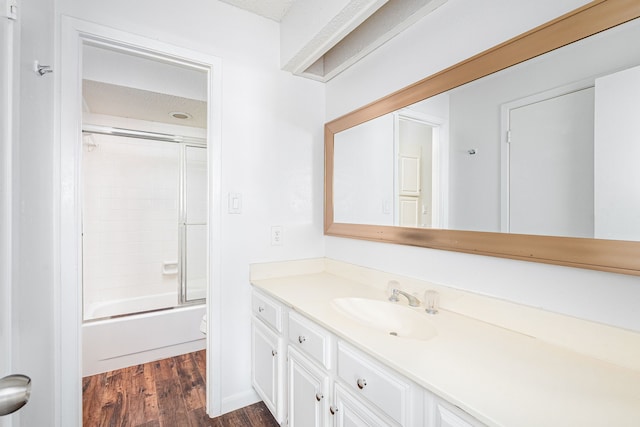 full bathroom featuring hardwood / wood-style flooring, vanity, toilet, and bath / shower combo with glass door