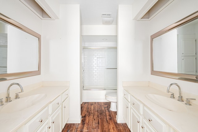 full bathroom with enclosed tub / shower combo, vanity, toilet, and hardwood / wood-style floors