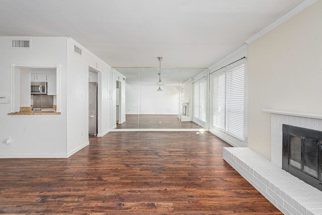 unfurnished living room featuring crown molding, dark hardwood / wood-style floors, and a brick fireplace