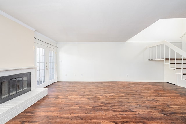 unfurnished living room with crown molding, a fireplace, dark hardwood / wood-style floors, and french doors