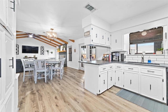 kitchen with tasteful backsplash, white cabinets, kitchen peninsula, and vaulted ceiling with beams