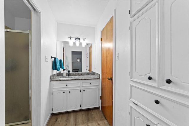 bathroom with vanity, hardwood / wood-style floors, and a shower with door