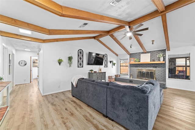 living room with lofted ceiling with beams, ceiling fan, light wood-type flooring, and a fireplace