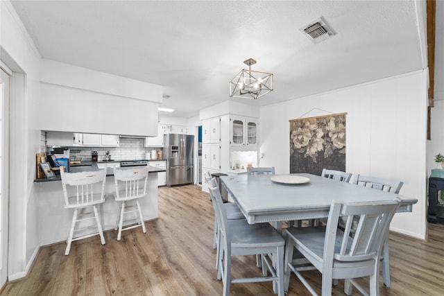 dining area with a notable chandelier, a textured ceiling, and light hardwood / wood-style flooring