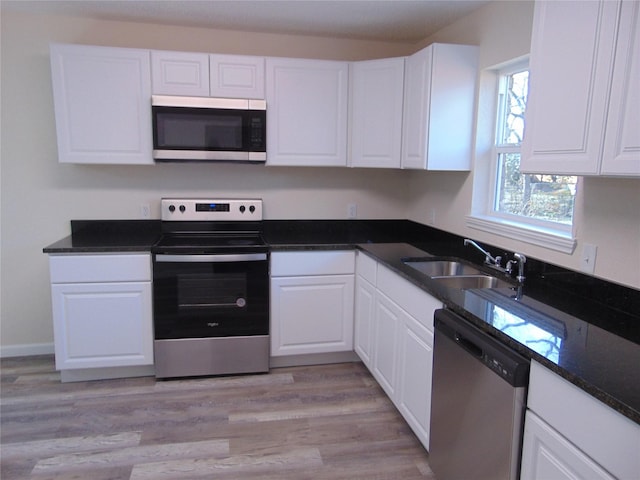 kitchen with light wood-type flooring, stainless steel appliances, sink, and white cabinets