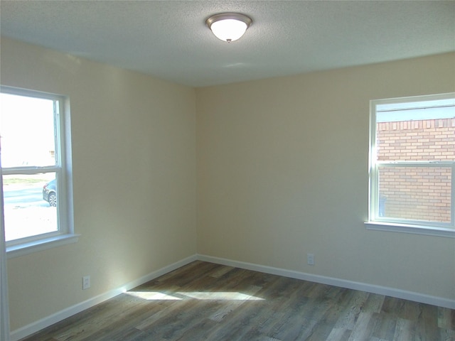 spare room featuring hardwood / wood-style flooring, a textured ceiling, and a wealth of natural light