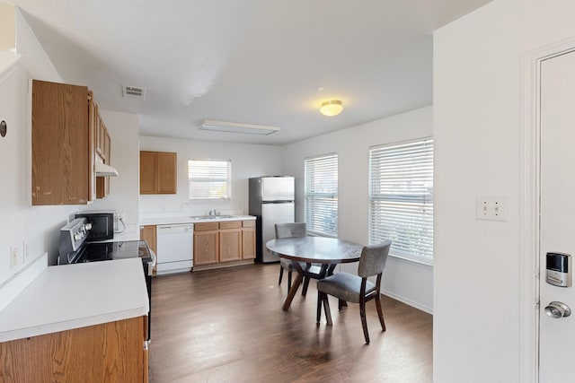 kitchen featuring sink, stainless steel refrigerator, dark hardwood / wood-style floors, white dishwasher, and range with electric stovetop