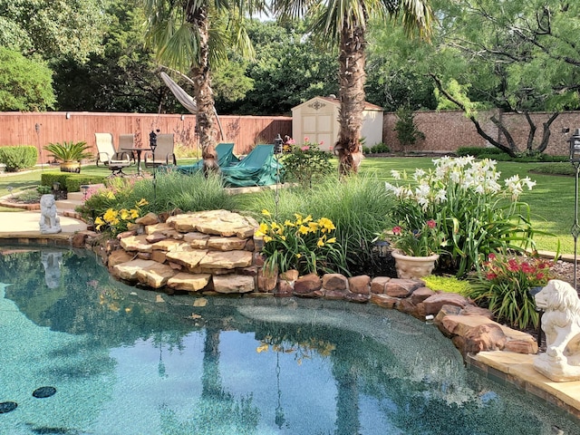 view of pool featuring a lawn and a storage unit