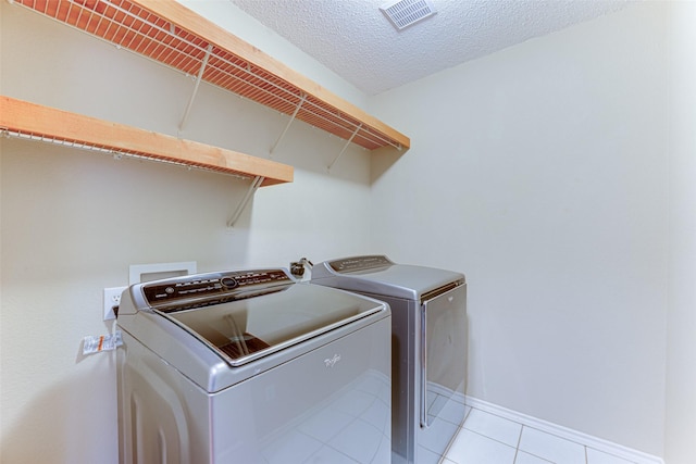 laundry room with independent washer and dryer, a textured ceiling, and light tile patterned floors