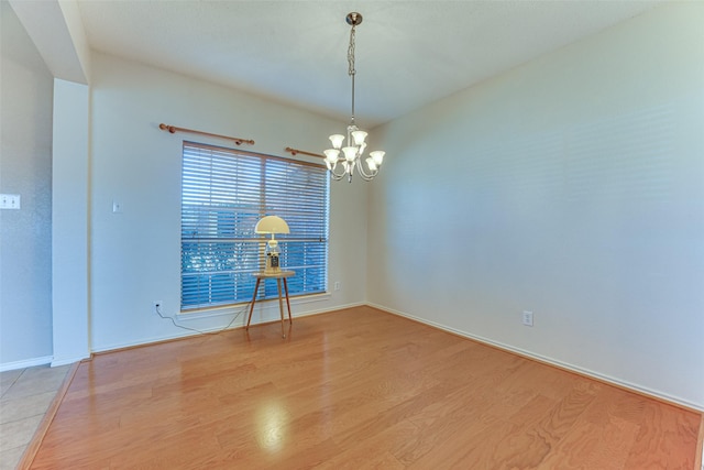 empty room with light hardwood / wood-style flooring and a notable chandelier