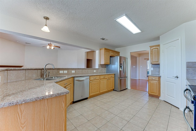 kitchen with light brown cabinetry, sink, kitchen peninsula, stainless steel appliances, and backsplash