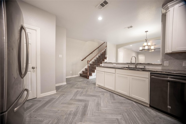 kitchen featuring sink, hanging light fixtures, dark stone counters, stainless steel appliances, and white cabinets