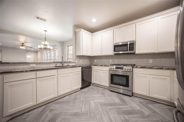 kitchen with sink, dark stone countertops, pendant lighting, stainless steel appliances, and white cabinets