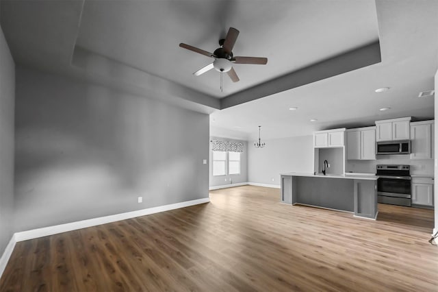 kitchen featuring a sink, light wood-style floors, open floor plan, baseboards, and appliances with stainless steel finishes