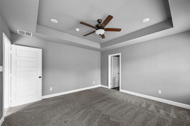 carpeted empty room featuring baseboards, visible vents, and a tray ceiling