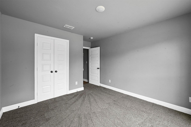 unfurnished bedroom featuring dark colored carpet, a closet, visible vents, and baseboards