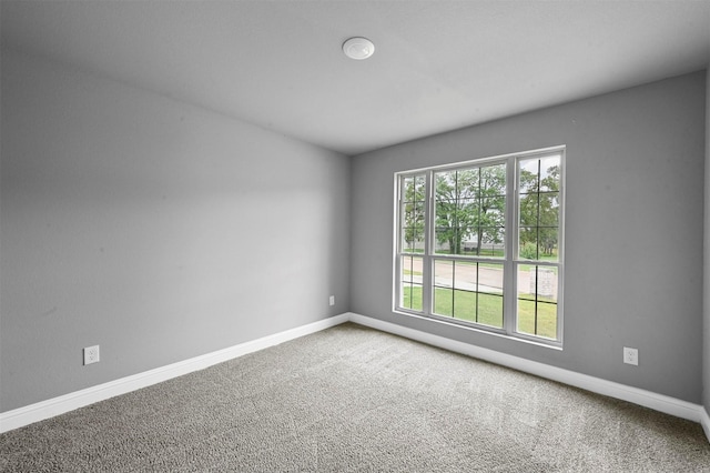 carpeted spare room featuring a healthy amount of sunlight and baseboards