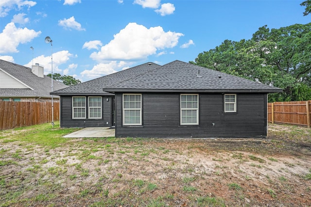 rear view of house featuring a shingled roof, a fenced backyard, and a patio