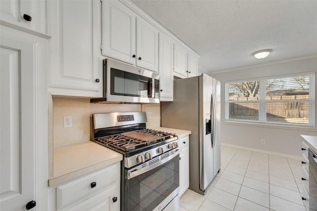 kitchen with white cabinetry, crown molding, a textured ceiling, light tile patterned floors, and appliances with stainless steel finishes